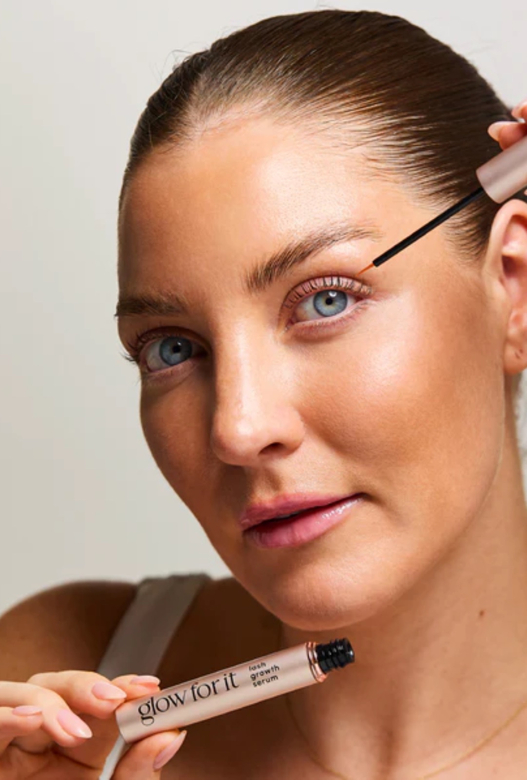 Model applying Glow For It lash growth serum